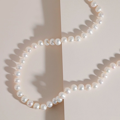 a white pearl strand necklace on a white background 